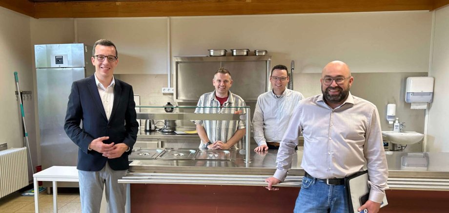 Erster Kreisbeigeordneter und Schuldezernent Patrick Krug (von links) präsentiert gemeinsam mit Schulleiter Nils Strowitzki, Matthias Röse, Leiter des Amts für Schulische Bildung und Betreuung, und Stefan Schmidt, dem Leiter des Amtes für Hochbau, Energie und Gebäudewirtschaft, die neue Essensausgabe an der Grundschule in Kirtorf.