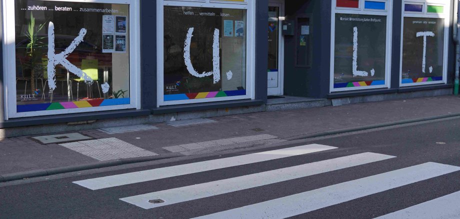 Die Fassade und Schaufenster der KULT-Beratungsstelle. Im Vordergrund ist eine Straße mit Zebrastreifen zu sehen