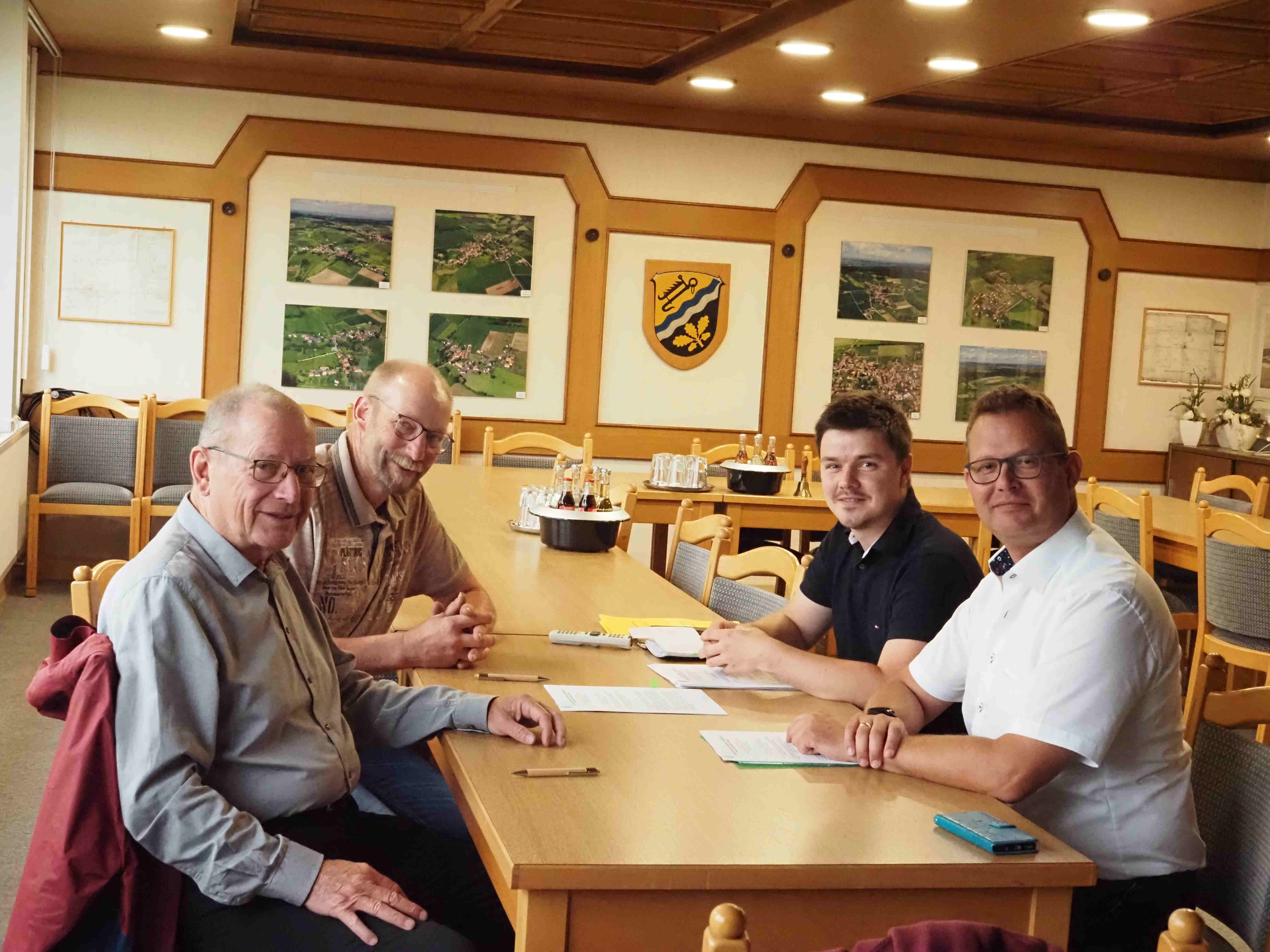 Karl-Heinz Zobich (von links), Christoph Hardt (beide NLV e.V.), Projektleiter Johannes Euler und der Schwalmtaler Bürgermeister Timo Georg bei der Vertragsunterschrift. Sie sitzen in einem Rathaussaal. 