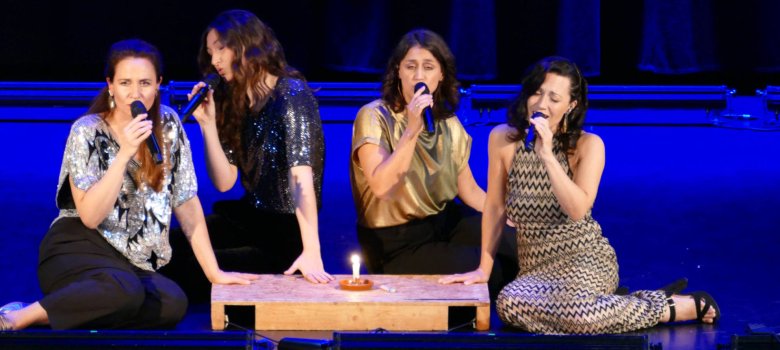 Vier Sängerinnen sitzen auf dem Bühnenboden und singen ein einfühlsames A-Cappella-Lied