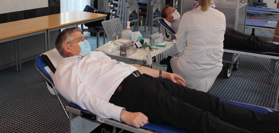 Landrat Görig und Erster Kreisbeigeordneter spenden gemeinsam Blut. Sie liegen auf Behandlungsliegen.