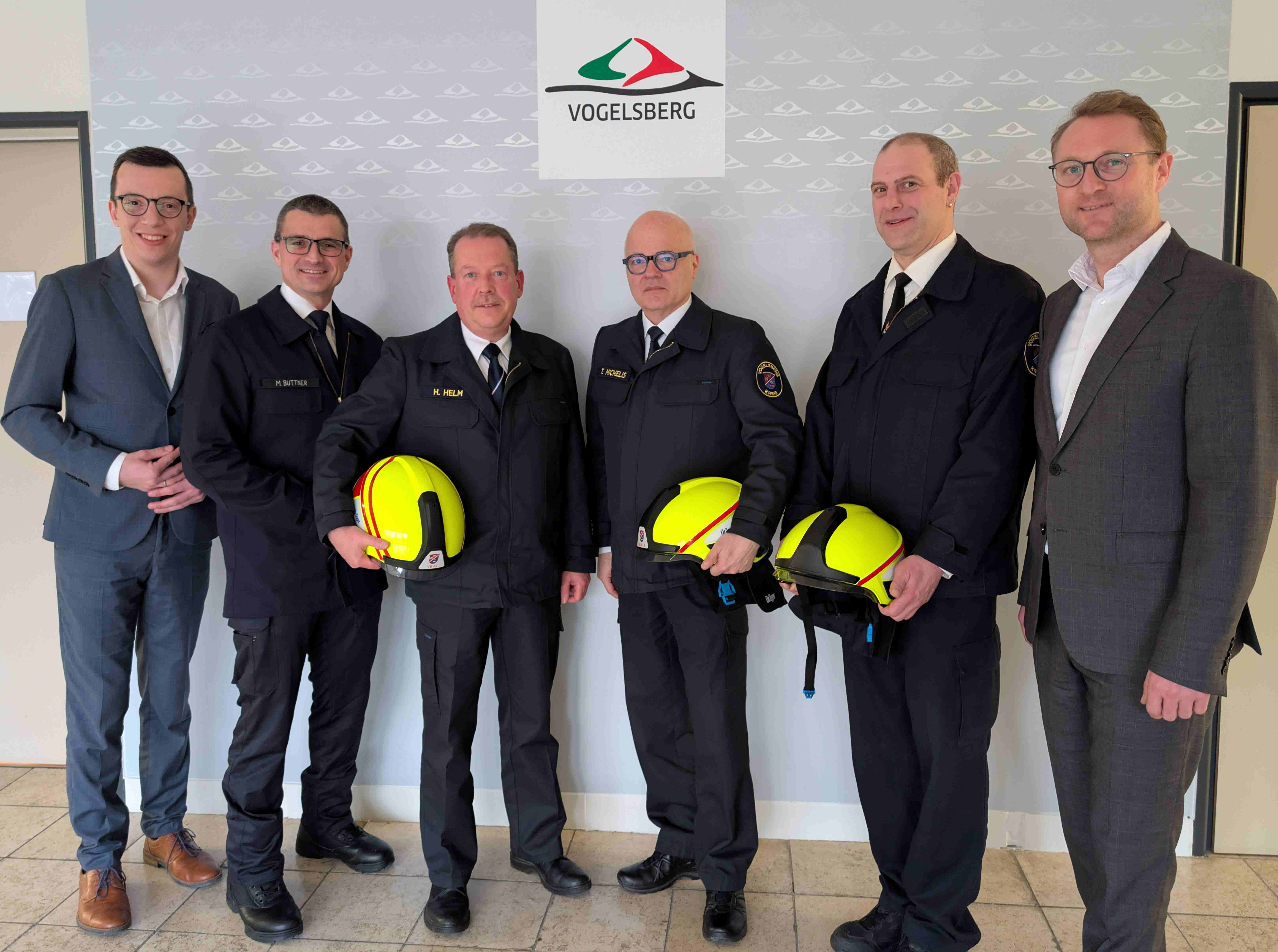 Sechs Männer haben sich zum Gruppenbild aufgestellt. Vier von ihnen tragen Feuerwehruniform. 