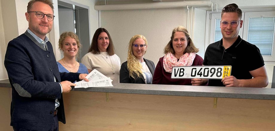 Landrat Dr. Jens Mischak (von links) gemeinsam mit Luisa-Marie Schübeler, Jessica Scholtes, Katharina Lichtenberg, Laura Rose und Jannik Schneeberger, allesamt vom Amt für Ordnungs- und Straßenverkehrsangelegenheiten, am neuen Serviceschalter im Untergeschoss der Verkehrsbehörde in der Bahnhofstraße 79 in Lauterbach.