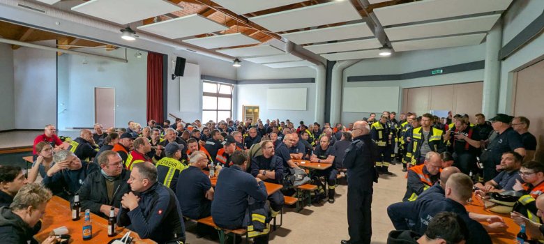 Blick in ein vollbesetztes Bürgerhaus. Einsatzkräfte warten aufs Mittagessen