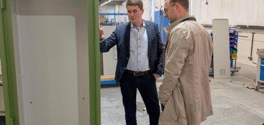 Zwei Männer stehen an einem Schaltschrank und sprechen darüber