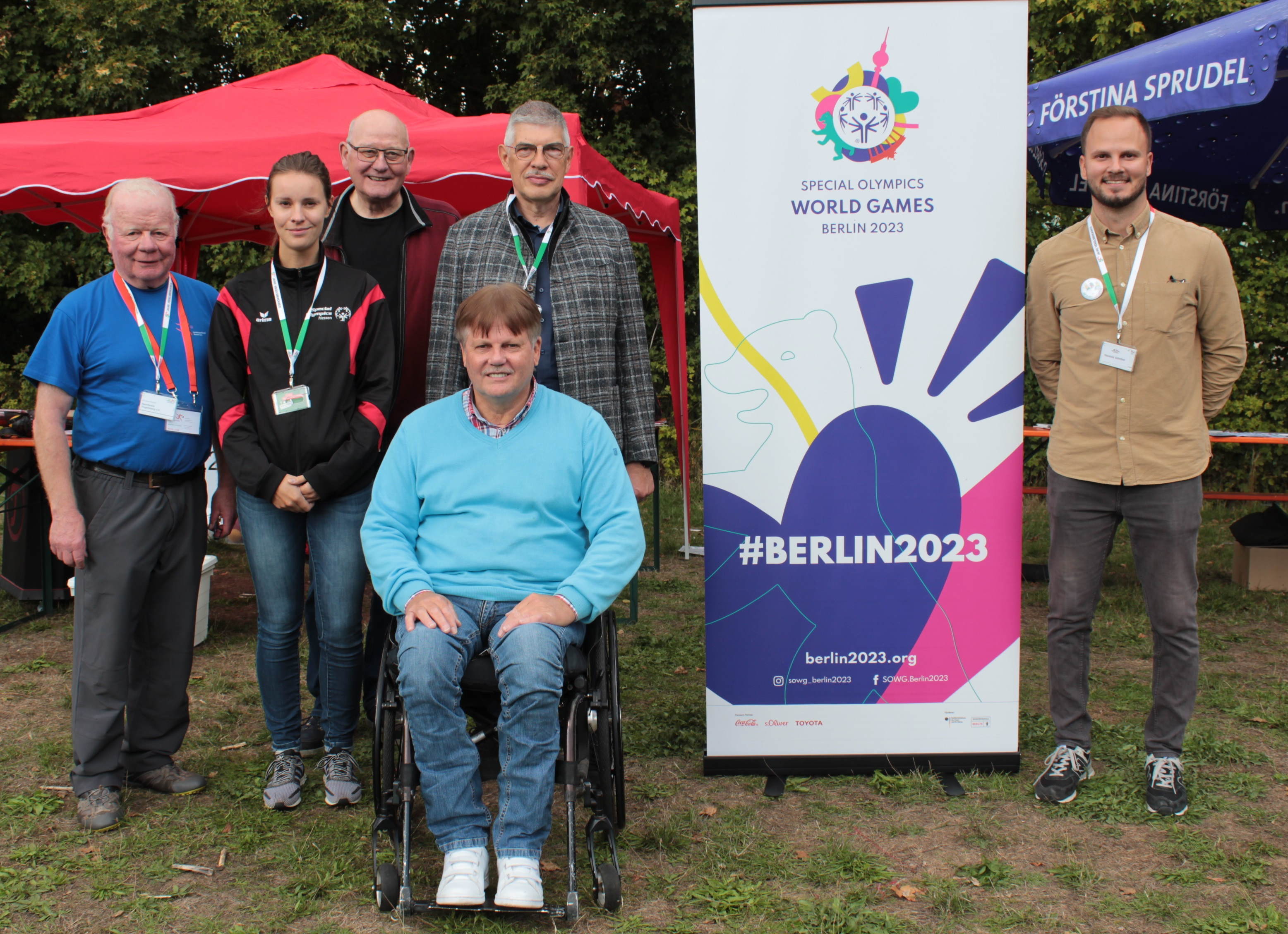 Sechs Menschen haben sich an einem Aufsteller zum Gruppenbild postiert. Sie werben für die Special Olympic World Games 2023 in Berlin