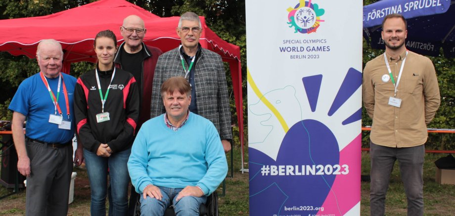 Sechs Menschen haben sich an einem Aufsteller zum Gruppenbild postiert. Sie werben für die Special Olympic World Games 2023 in Berlin