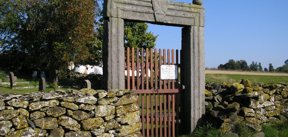 Ein Sandsteinportal am Zugang zu einem alten Friedhof in Weidmoos. 