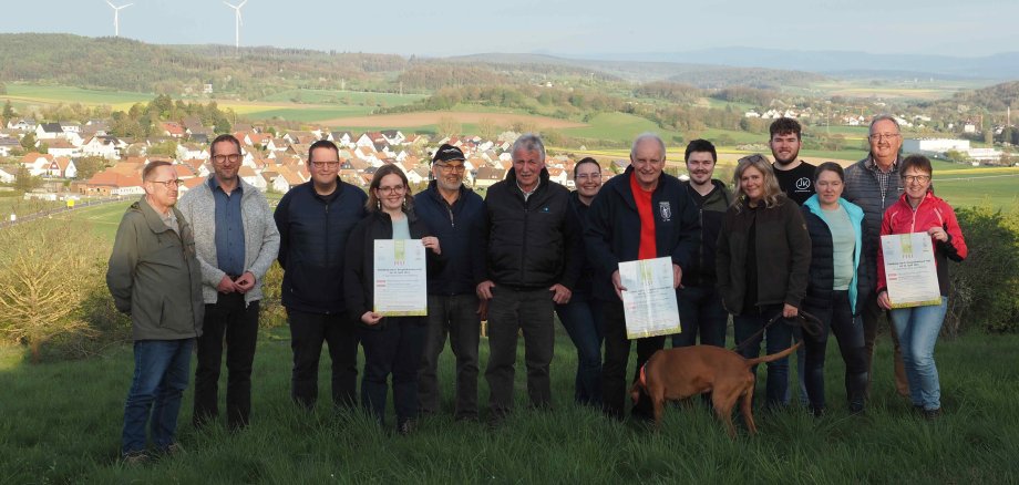 Ronny Mohr (Zweiter von rechts), Kommissarischer Leiter des Amtes für Wirtschaft und den ländlichen Raum des Vogelsbergkreises, und Johannes Euler (Sechster von rechts), Projektleiter Naturschutzgroßprojekt Vogelsberg, und Silke Grünewald (Achte von rechts), Stadtverwaltung Lauterbach, gemeinsam mit Vertreterinnen und Vertretern der teilnehmenden Vereine und Organisationen am „Hälsberg“ mit Blick auf Maar und Lauterbach.