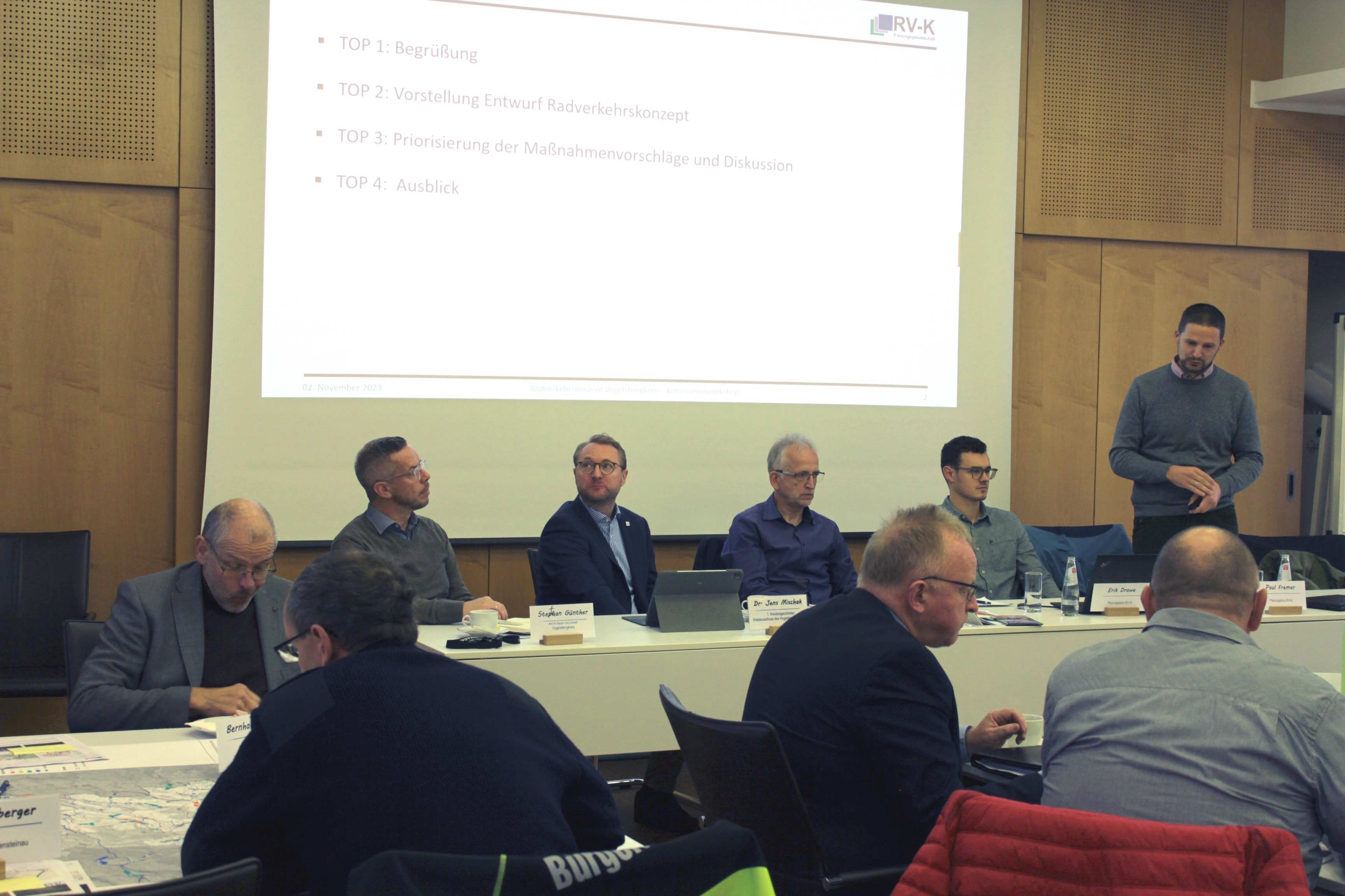 Im Sitzungssaal des Vogelsbergkreises findet ein Workshop für das Radverkehrskonzept des Vogelsbergkreises statt. auf dem Foto sind einige Herren zu sehen, die einem Referenten zuhören