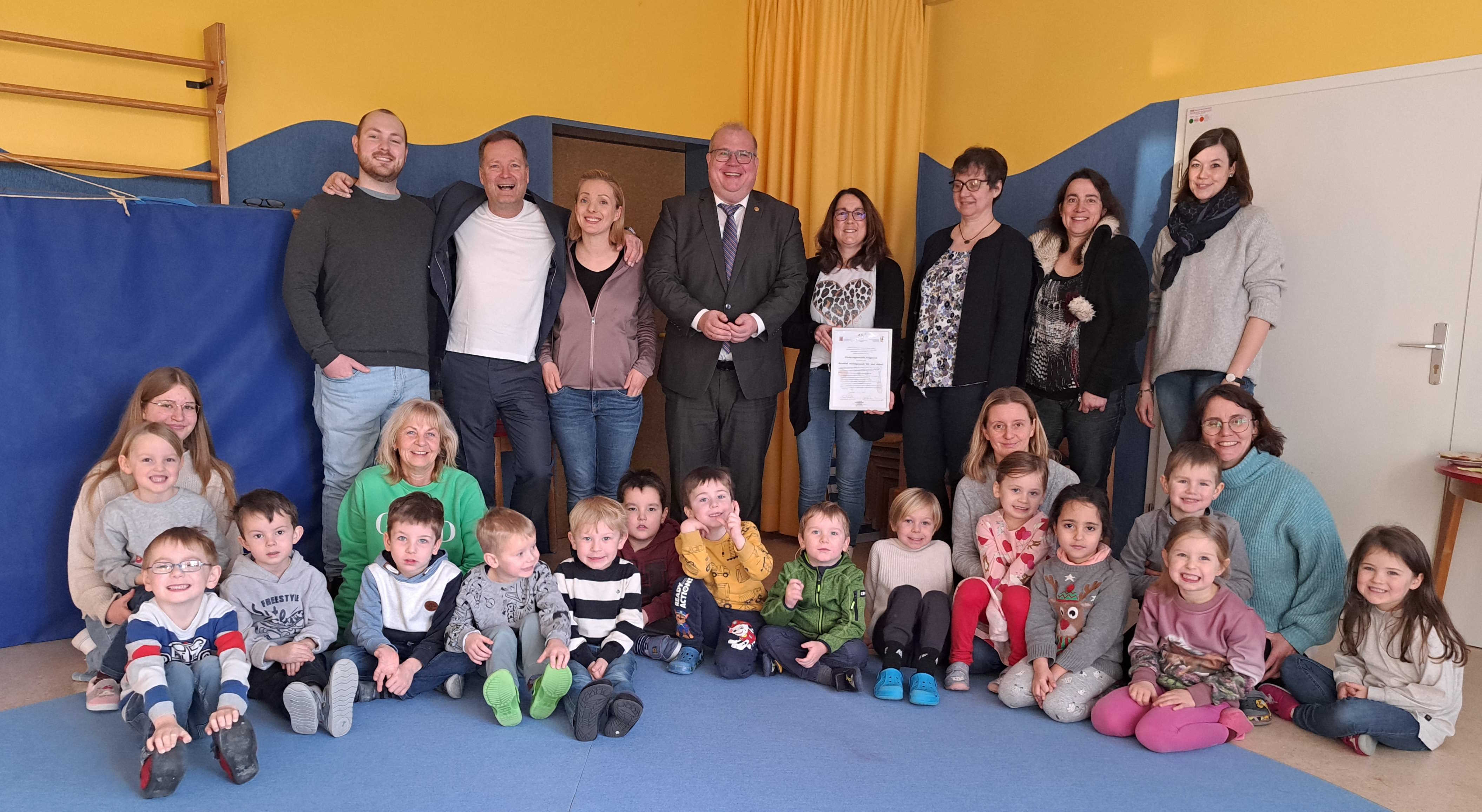 Freuen sich über die Auszeichnung (von links): Zahnarzt Luc Sayffaerth, der neu in die Praxis seines Vaters eingestiegen ist, Dr. Klaus Sayffaerth mit Tochter Kim Röther, die als Praxismitarbeiterin mit dem Vater die Kita als Patenschaftsteam betreut, Bürgermeister Stephan Paule, Kita-Leiterin Nicole Weitzel, Uta Born vom Arbeitskreis Jugendzahnpflege Vogelsberg, Dr. Sonja Schmidt-Schäfer, Schulzahnärztin im Gesundheitsamt, Carolin Rehm als Mitglied des Elternbeirates sowie Kinder und Mitarbeiter der Kita.