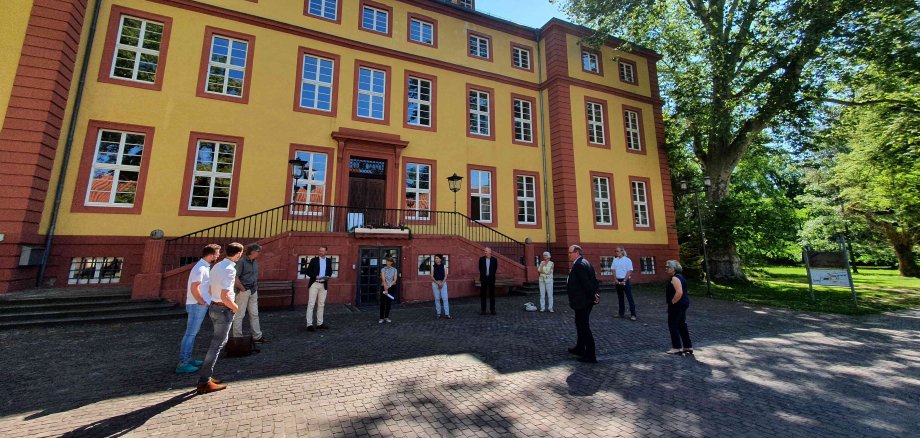 Gruppenbild bei der Bescheidübergabe. Im Hintergrund das gelbe Schloss Hallenburg in Schlitz.