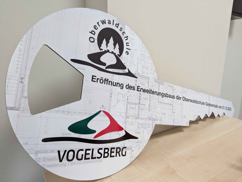 Ein überdimensional großer Schlüssel, der symbolisch an die Oberwaldschule überreicht wurde. Darauf sind die Logos der Schule und des Vogelsbergkreises zu sehen