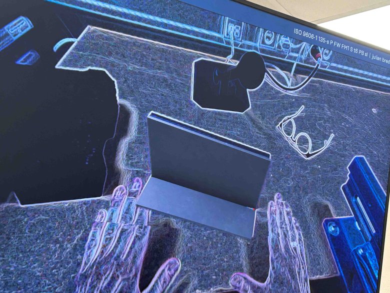 Blick durch eine Augmented-Reality Brille. Sie bildet die Realität schemenhaft hab. auf einem Tisch liegen verschiedene Sachen udn sind schwarz-weiß dargestellt.