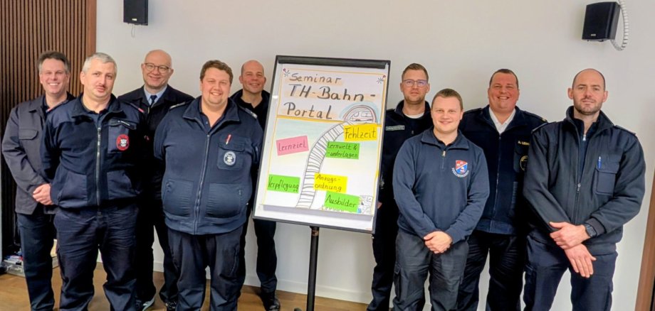 Auch Vogelsberger Feuerwehrleute konnten an der speziellen Schulung M Rettungszug der Bahn teilnehmen. Knapp zehn Männer lächeln in Feuerwehrdienstkleidung in die Kamera.