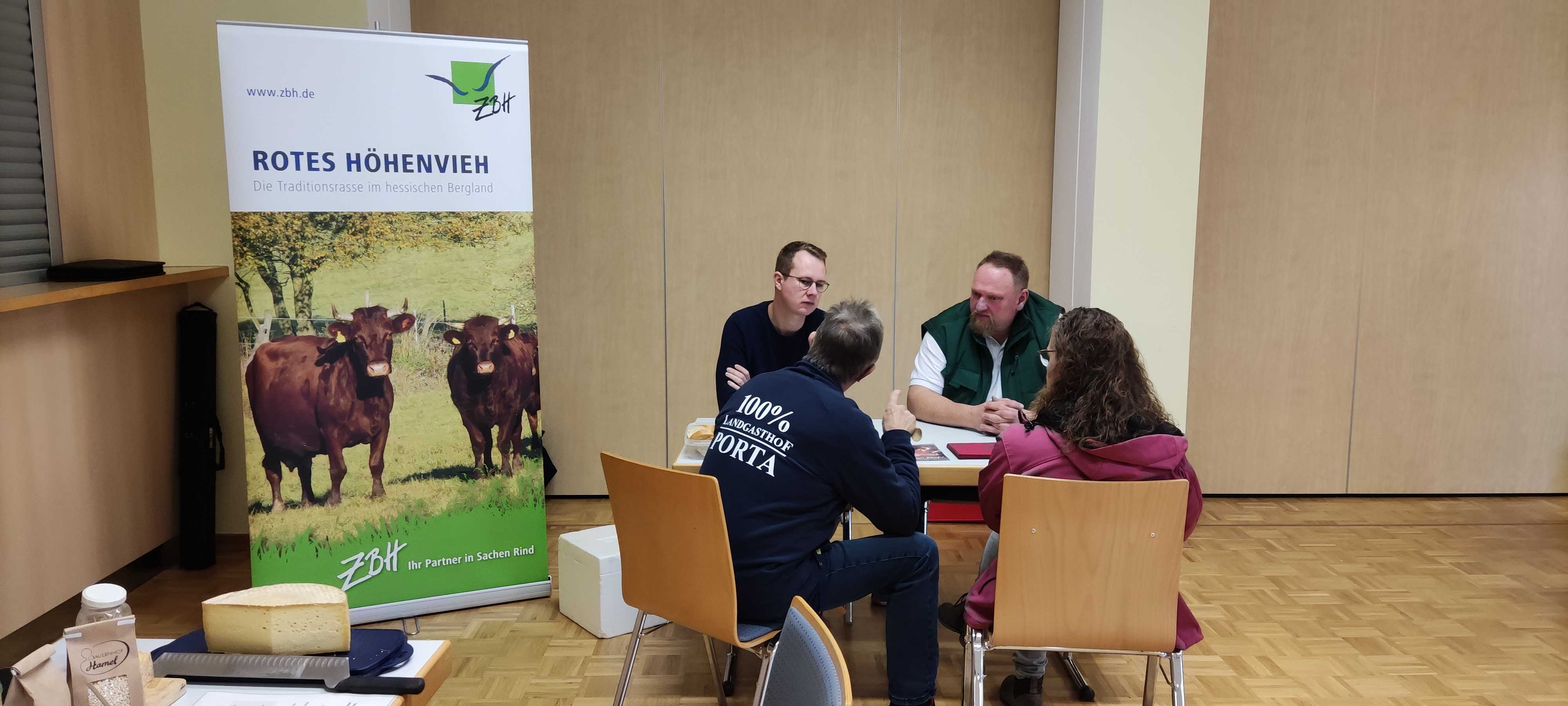 Vier Menschen sitzen an einem Tisch und tauschen sich zu direkt vermarkteten Lebensmitteln aus. 