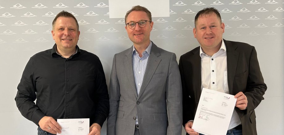 Landrat Dr. Jens Mischak kann Matthias Glitsch (links) und Oliver Kröll (rechts) Zuschüsse der Ovag überreichen.