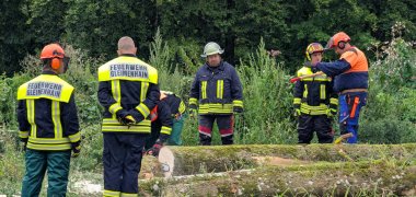 mehrere Männer in Schutzkleidung üben den Umgang mit Motorsägen