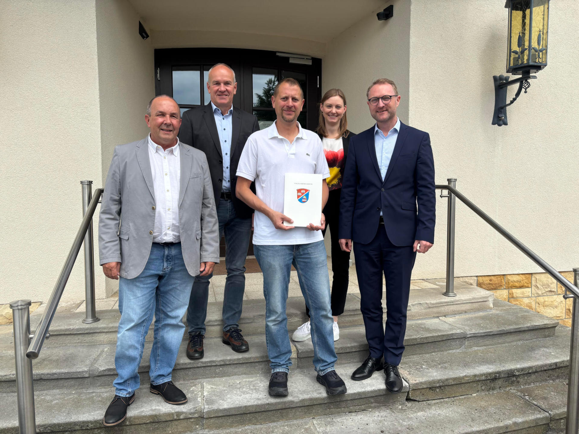 Landrat Dr. Jens Mischak (rechts) übergibt gemeinsam mit Matthias Steckenreuter (von links), Regionalmanagement beim Verein Region Vogelsberg, Edwin Schneider, Vorsitzender des LEADER-Beirats, und Jana Brittner, Leiterin des Sachgebiets Dorf- und Regionalentwicklung im Amt für Wirtschaft und den ländlichen Raum des Vogelsbergkreises, einen Förderbescheid an Jens Lerner aus Hartershausen.
