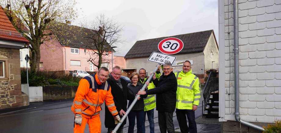 Tempo 30 ist ab sofort tagsüber Pflicht. Im Bereich der Kindertagesstätte Engelrod gilt unter der Woche nun ein Tempolimit. Landrat Manfred Görig (Zweiter von rechts), gemeinsam mit Peter Lippert (von rechts), Leiter vom Regionalen Verkehrsdienst der Polizeidirektion Vogelsberg, Uwe Kraft, Leiter des Amtes für Straßenverkehrsangelegenheiten, Kita-Leiterin Wilma Stein, Bürgermeister Dieter Schäfer, und Streckenwart Matthias Stier beim Aufstellen der Beschilderung in Engelrod.