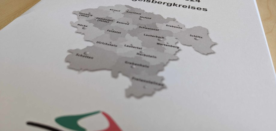 Aufnahme des Deckblatts des Kreishaushaltes 2024. Darauf zu erkennen eine Karte des Vogelsbergkreises und das Logo. Ein stilisierter Vulkan mit schwarzen, roten und grünen Linien