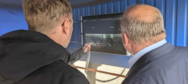 Landrat Dr. Mischak und Bürgermeister Paule verfolgen am Bildschirm die Infrarotaufnahmen aus dem Innern des „Fire Dragon 9000“.