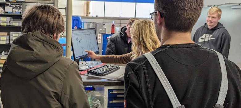 Katharina Schmitt (Mitte), Personalreferentin, erläutert an einem PC-Bildschirm das System, das hinter der Lagerlogistik steckt.