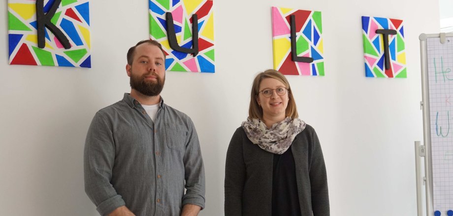 „Wir sind K.U.L.T.“: Die Sozialarbeiter Daniela Christ und Simon Thiel bilden das „K.U.L.T.“-Team. Sie haben sich niedrigschwellige Beratung in vielen Lebenslagen auf die Fahnen geschrieben. Sie stehen vor einer weißen Wand. 