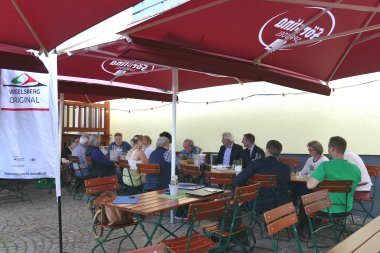 Die Jury und einige Erzeugerinnen sprechen mit Vertreterinnen von der Presse. Sie sitzen in einem Biergarten.