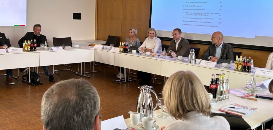 Eine Gruppe von Menschen sitzt in einem Sitzungssaal.  