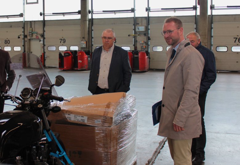 Erster Kreisbeigeordneter Dr. Jens Mischak (rechts) lässt sich von Uwe Heinbach, Betriebsstättenleiter der Online Systemlogistik GmbH & Co. KG, Ware zeigen, die durch das Logistikunternehmen in ganz Europa verschickt werden kann.