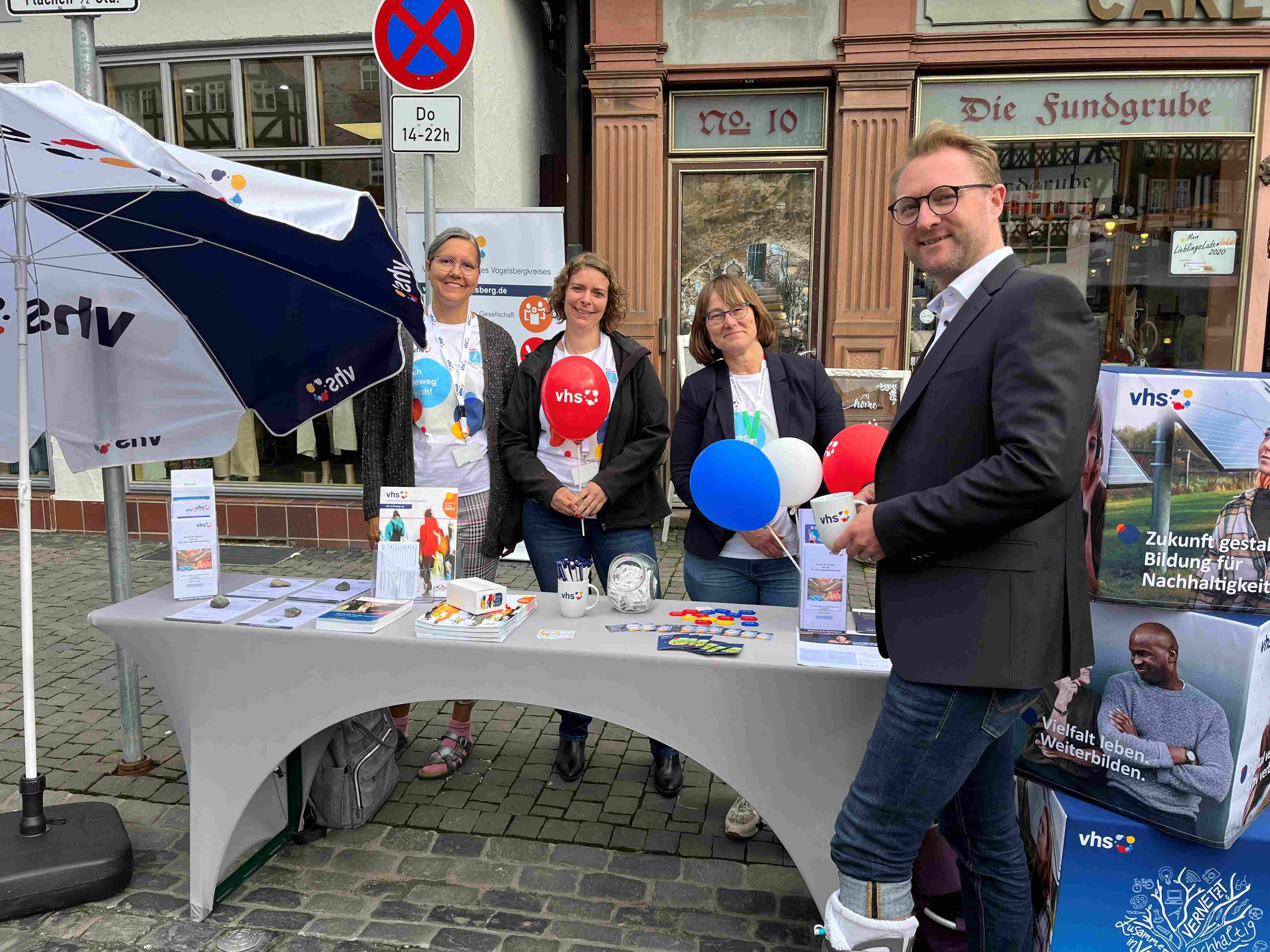 Dr. Jens Mischak steht an einem Info-Stand der volkshochschule in Alsfeld. GEmeinsam mit Monika Schenker, der Amtsleiterin, und zwei Mitarbeiterinnen