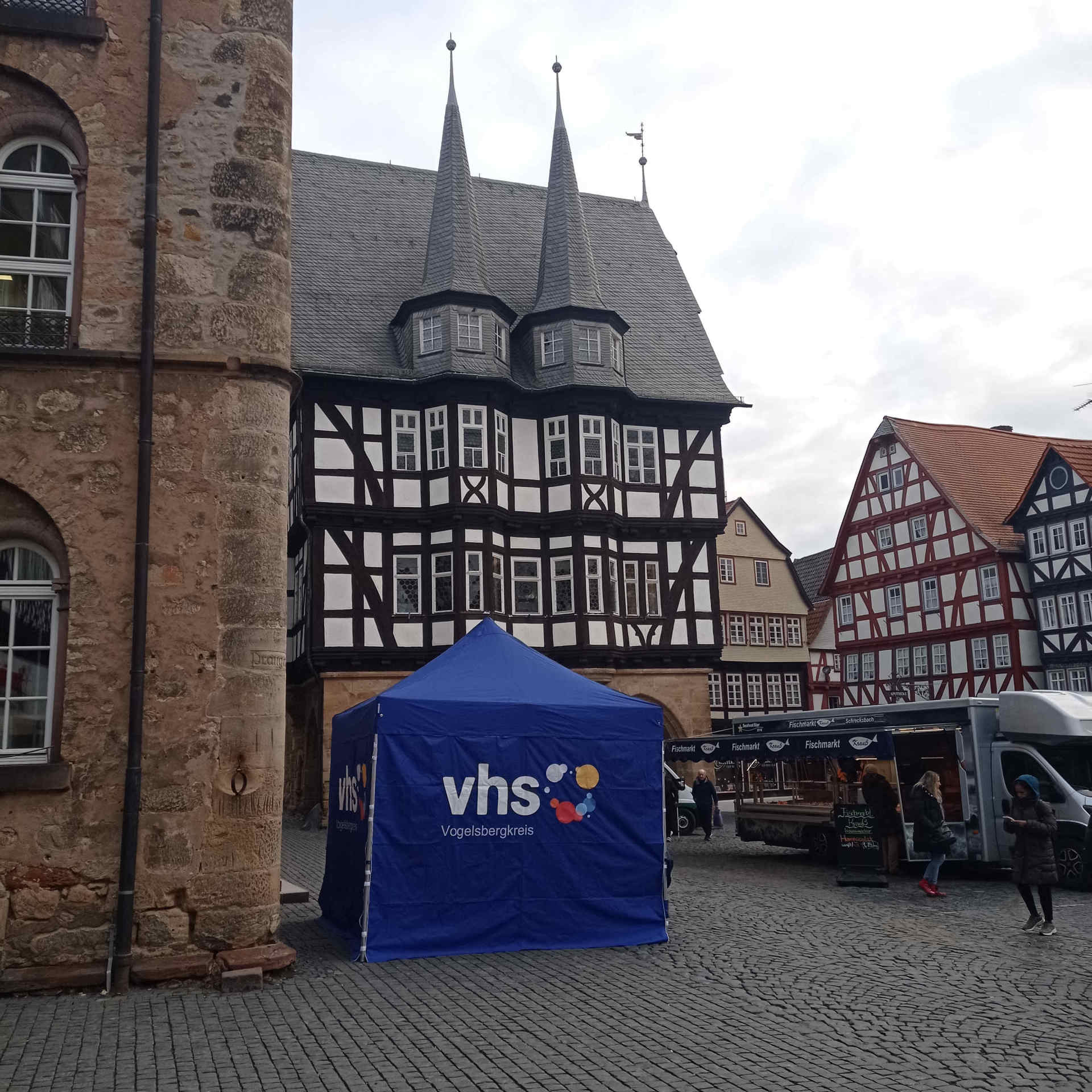Schon zu Beginn des Jahres war die vhs auf dem Alsfelder Wochenmarkt vertreten. Am Freitag, 28. August, haben Interessierte dort wieder die Möglichkeit, das Herbstsemester-Programm zu entdecken. Auf dem Foto ist ein blaues vhs-Pavillon vor dem Alsfelder Marktplatz zu sehen.