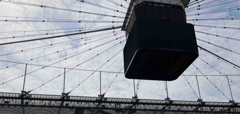 Foto aus dem Frankfurter Waldstadion. Zu sehen ist der große Anzeigewürfel, der über dem Spielfeld an der Dachkonstruktion hängt
