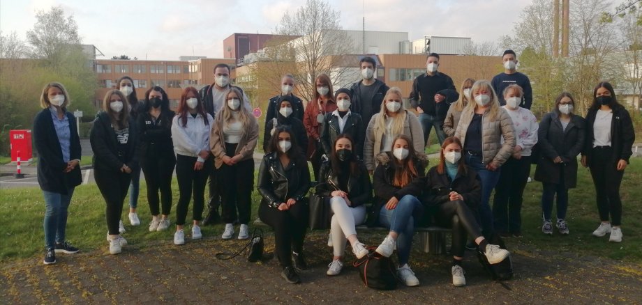 Karen Heipel und die Schüler des Unterkurses der Krankenpflegeschule des Vogelsbergkreises in Alsfeld, die den Wettbewerb rund um die Ausstellung von Körperwelten gewonnen haben. Sie haben sich zu einem Gruppenbild mit FFP2Masken aufgestellt. Im Hintergrund ist das KReiskrankenhaus zu sehen