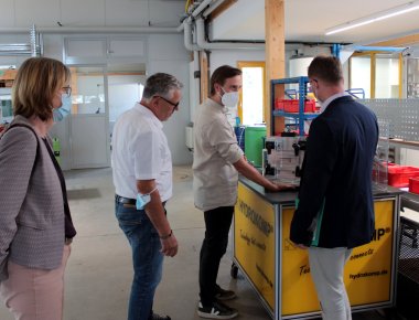 Erster Kreisbeigeordneter Dr. Jens Mischak (rechts) und Andrea Ortstadt von der Wirtschaftsförderung des Vogelsbergkreises, bekommen von Felix und Karl-Heinz Freund die Funktionsweise eines Spannelements erläutert. 