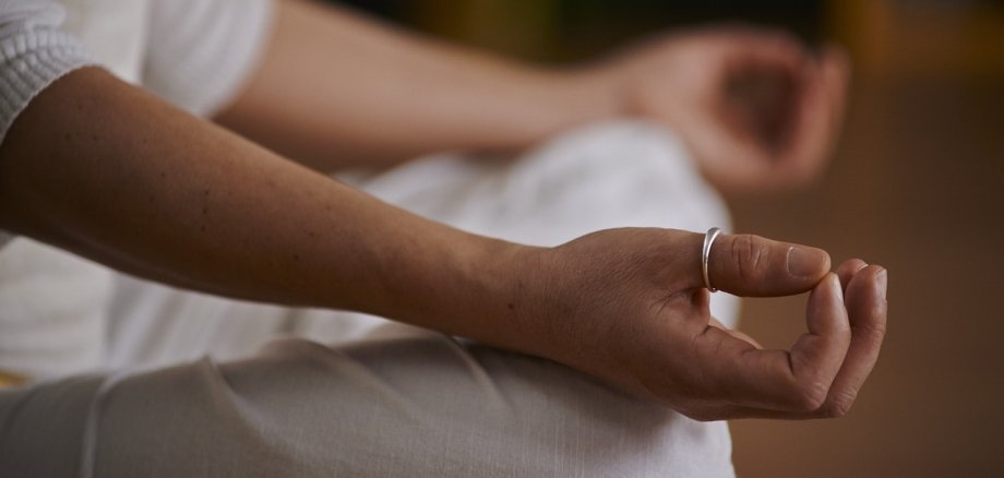 Eine Nahaufnahme einer Person im Yoga-Sitz. die Hände ruhen auf ihren Knien.